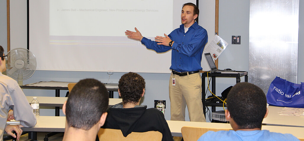 A professor actively engages a group of Electronic Equipment Technology Certificate students in a classroom.