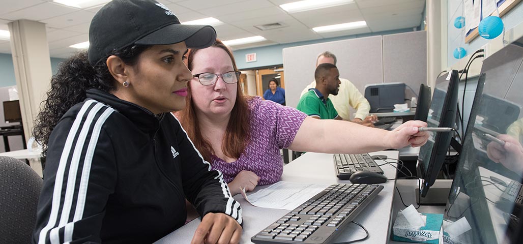 Two students exploring the upcoming classes for classes on a computer.