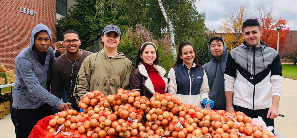 Group of NECC students stand behind table of food at the farmers market.