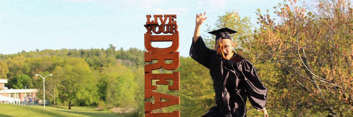 Student celebrating in front of Live Your Dreams sign at Commencement 2021