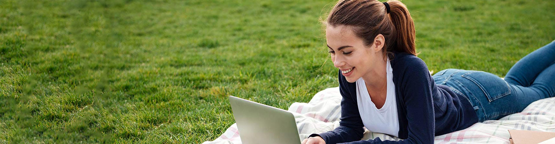 Student laying on the lawn working on her laptop
