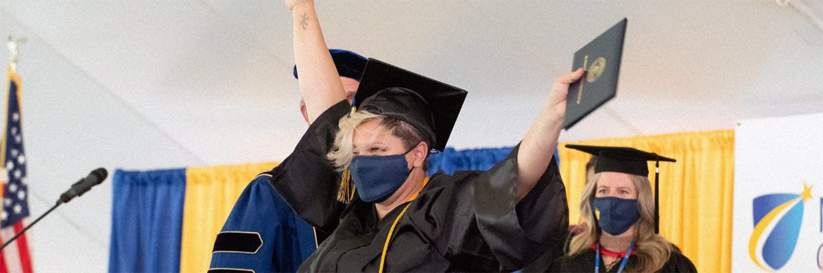 Student celebrating with diploma at 2022 commencement