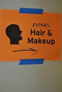 A sign shows movie extras where to report for hair and makeup.