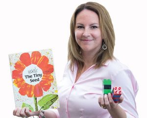 Jody Carson holding an Eric Carle Book and some legos.