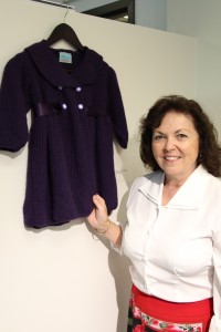 Susan Fichera exhibits a child's smock coat with satin ribbon that she knit.