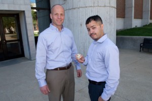 Veterans Services coordinator Jeffrey Williams (left) hands NECC U.S. Army Veteran and recent NECC graduate a challenge coin. 