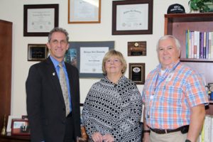 NECC President Lane Glenn, congratulates NECC employees Nancy Carroll, and Larry Rickabaugh.