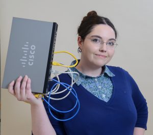 Computer Information Sciences Professor Adrianna Holden-Gouveia holding a Cisco device.