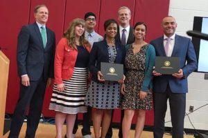 Marcy Vozella and Noemi Custodia-Lora accept the Early college designation from Gov. Baker. 