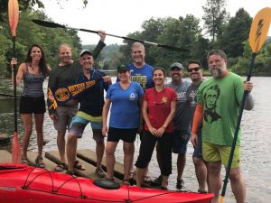 the members of the kayaking group stand next to a kayak.