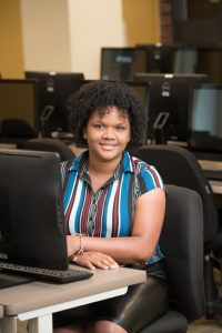 Kiara Santana Rosario sits at a computer in a computer classroom. 