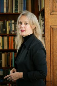 Elaine Scarry in all black with a bookcase behind her