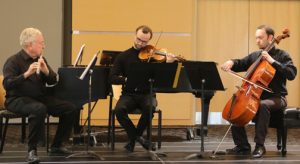 Members of the Essex Chamber Music Players are seated on stage playing their instruments