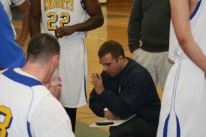 Stratton kneels with playbook among basketball players