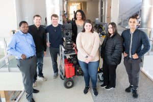 students and directors stand around camera equipment.