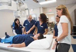 Rad tech students in a allied health classroom take instruction