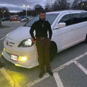 NECC graduate Jeurys Santiago standing in front of his car.