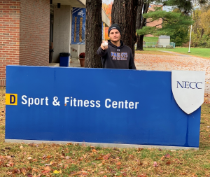 Student Athlete Mike Stellato standng in front of the NECC Sport a nd Fitness Center sign.