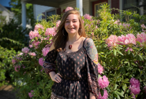 NECC 2020 grad Emily Forisso stands outside in front on a flowering bush.