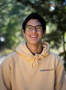 Smiling young man with glasses wearing yellow hoodie