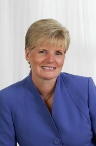 portrait of woman with short blonde hair wearing royal blue jacket.