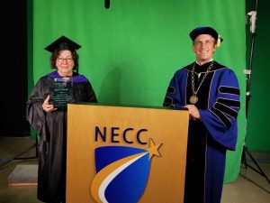 Man and woman holding award in academic regalia.