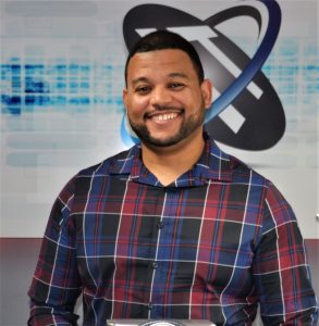 Young man wearing plaid shirt is smiling and looking at the camera.