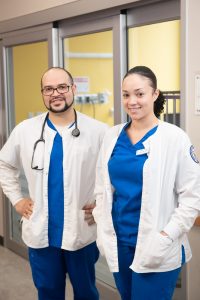 Two nursing students in white coats and scrubs.