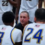 coach kneeling talking to sitting basketball players