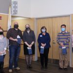 6 employees stand smiling at camera