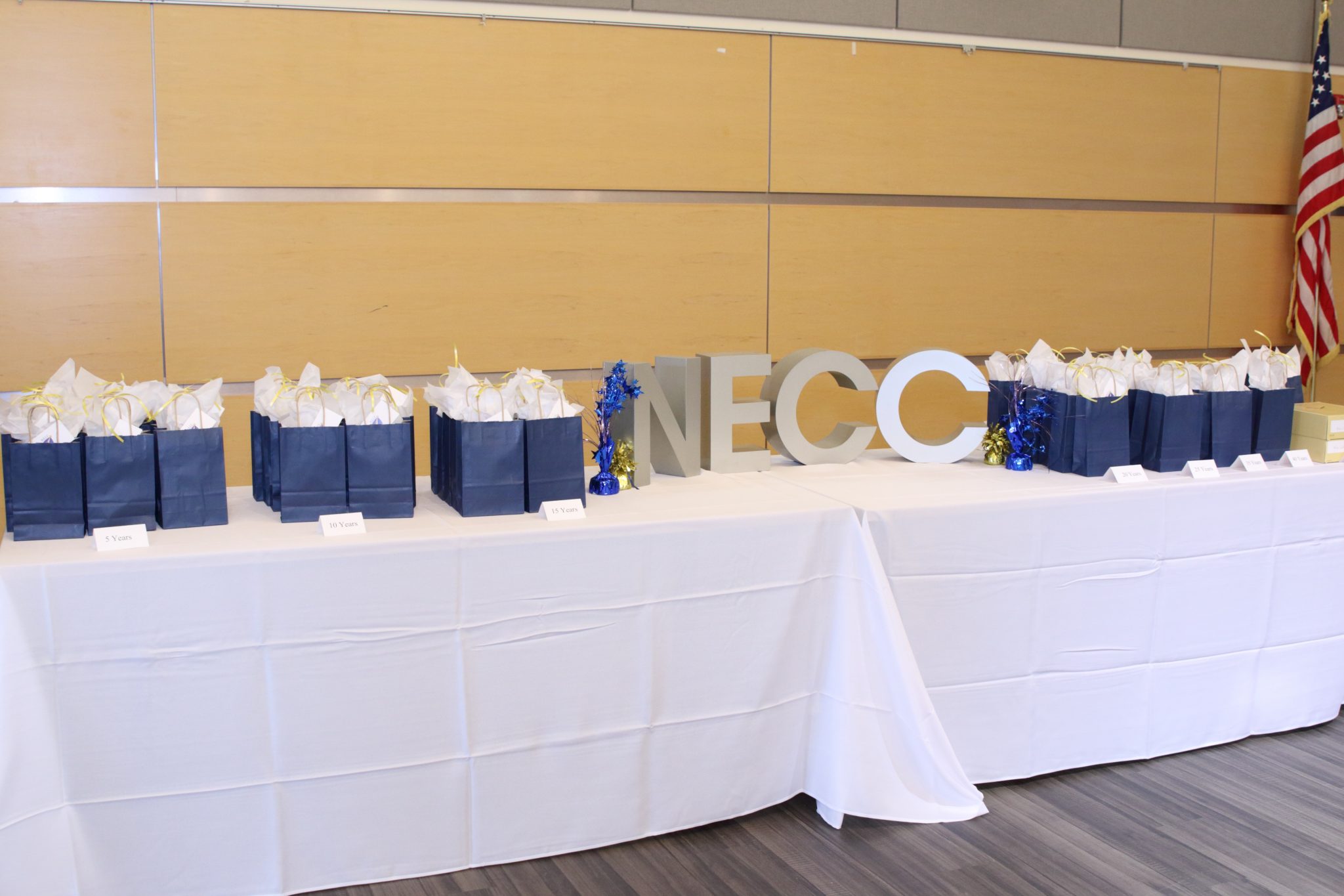 cloth covered table with blue gift bags and silver letters NECC