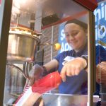 volunteer scoops popcorn from popcorn machine