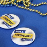 buttons that say NECC Giving day on a blue table cloth