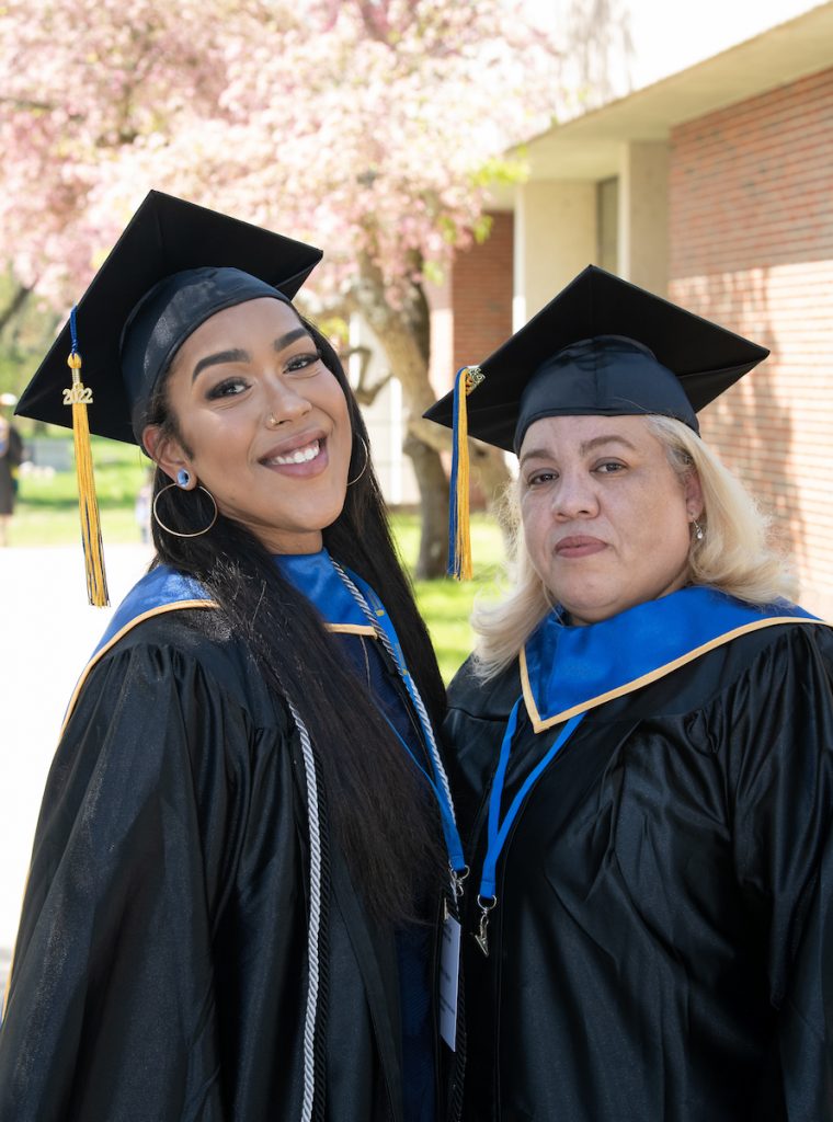 Daughter and Mother pose with graduation caps and gowns on