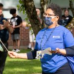 NECC Employee in blue shirt and yellow sunglasses holds pom pom