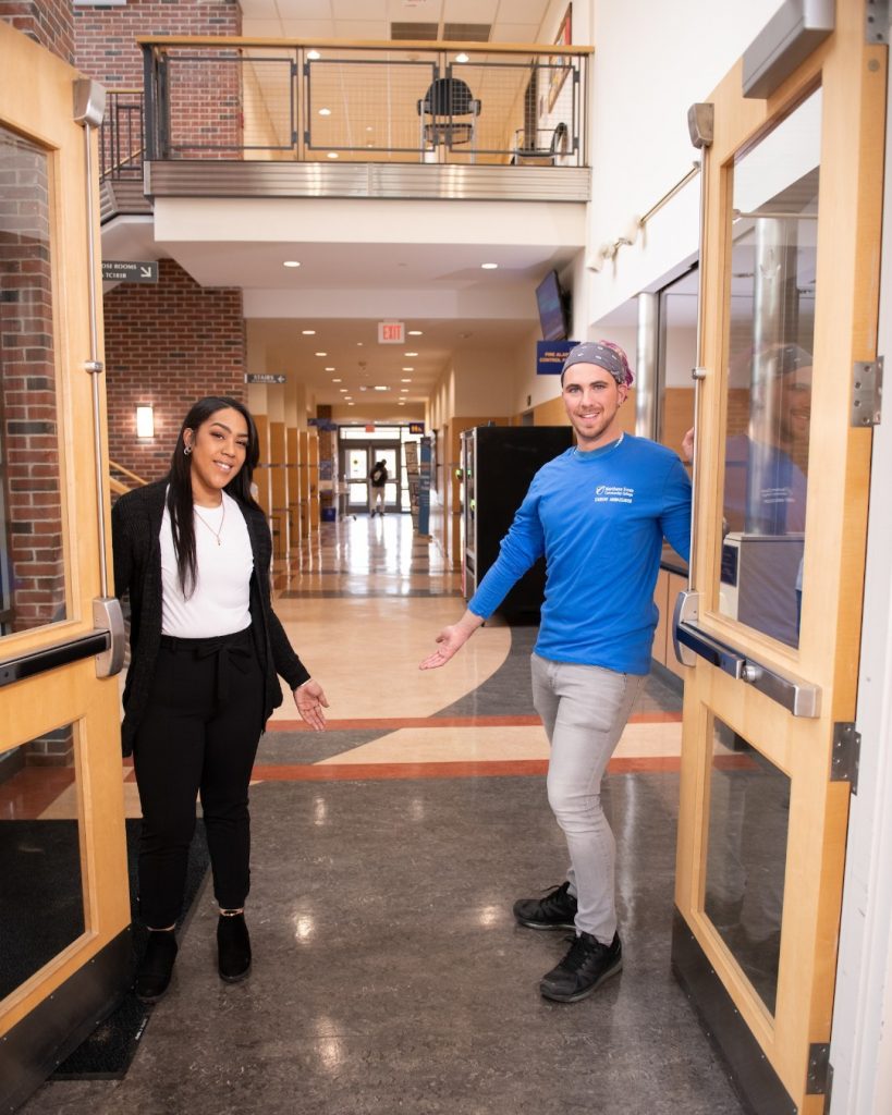 Chucha and Sean stand holding open two doors