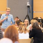 President Glenn listens to professor standing with microphone