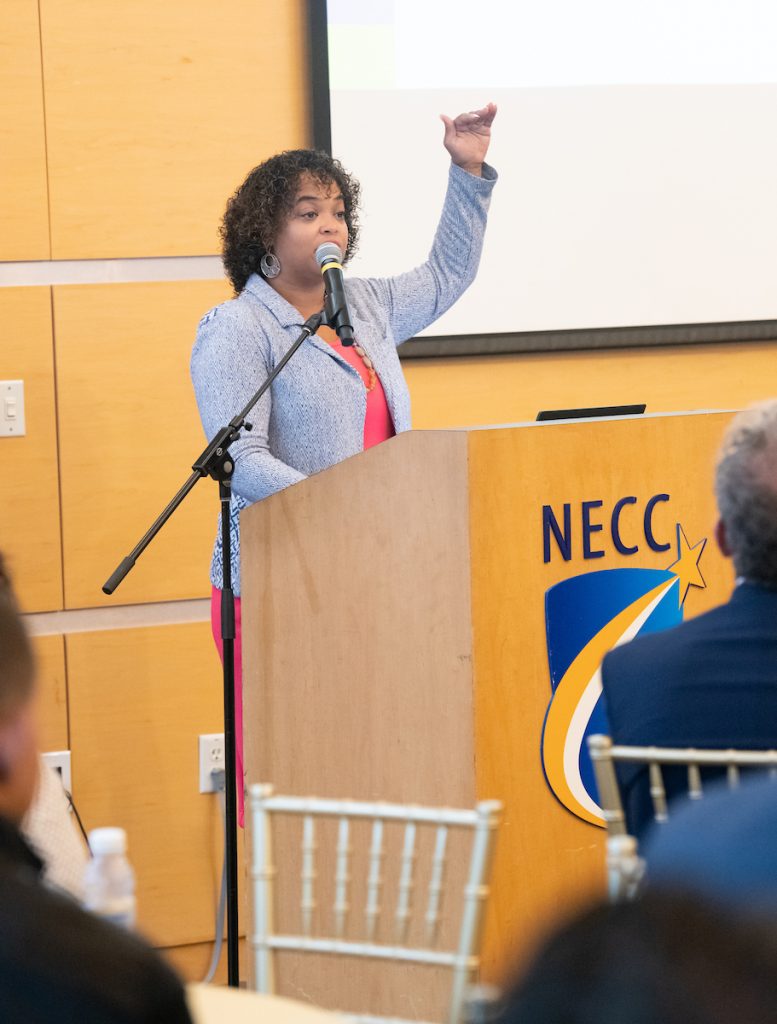 Francellis stands at podium and gestures to the sky