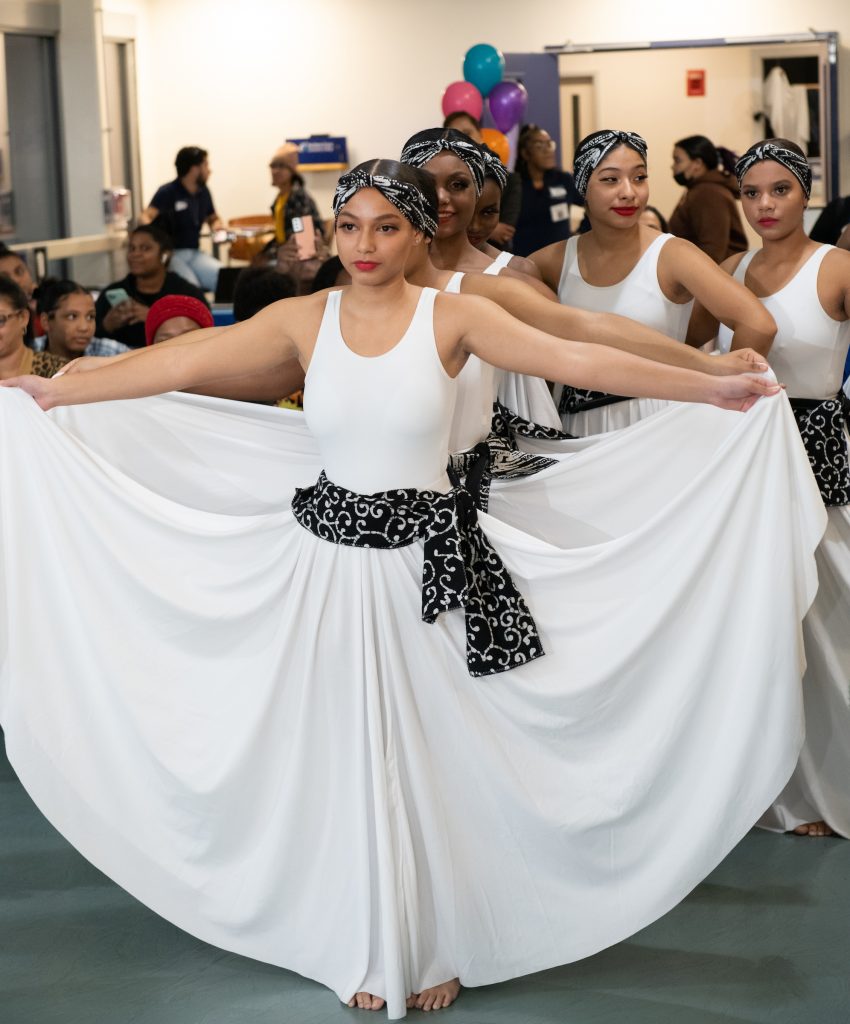 young ladies wearing white dresses line up to perform