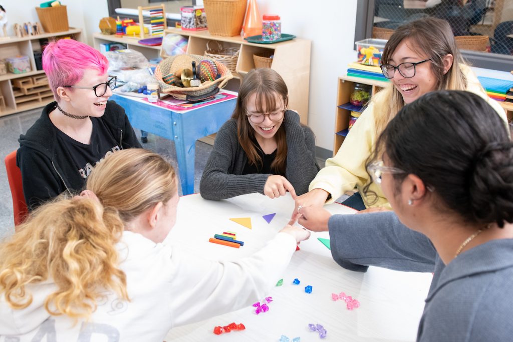 five college students gather around a table with counting manipulatives