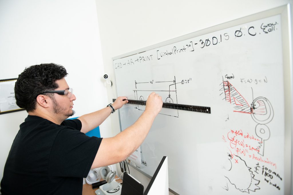 justin uses a yard stick to draw a straight line on a white board