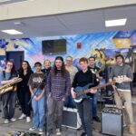students with instruments pose in fromt of mural in the Dimitry Building