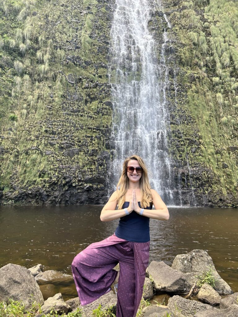 Heather stands on one leg in front of waterfall