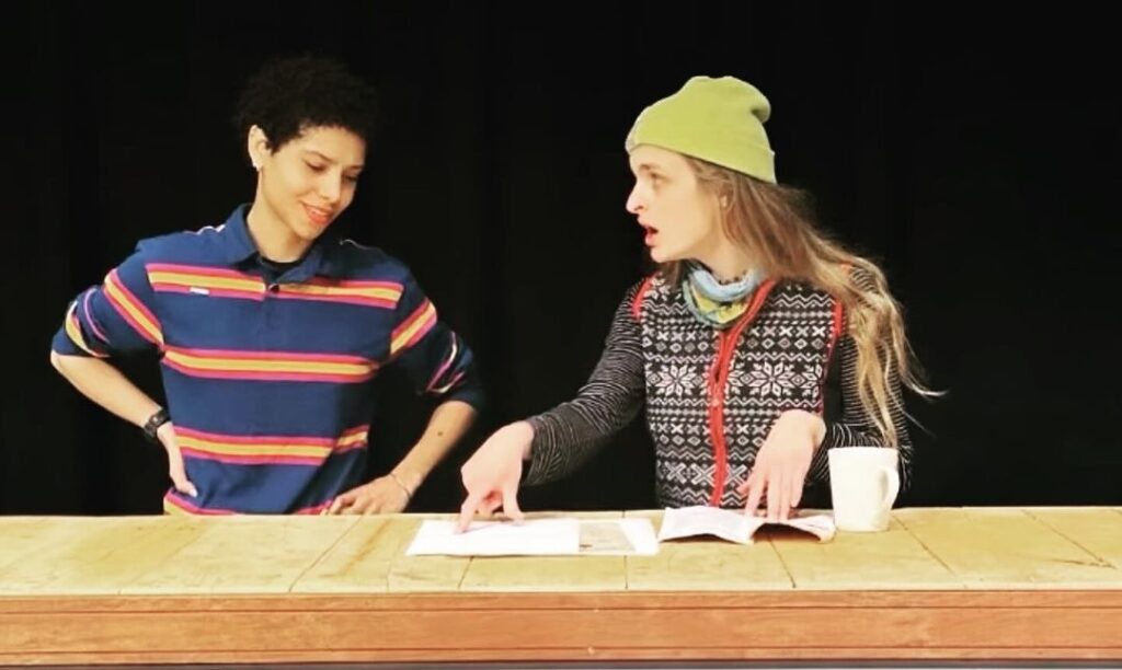 student in striped shirt goes over script with student in a beanie cap