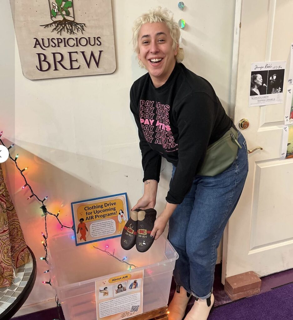 caitlin adding shoes to a shoe bin for the Arts In Reach clothing drive