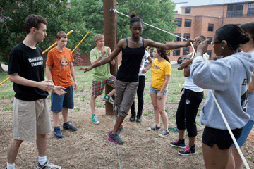 A girl walks a tight rope in a team building exercise