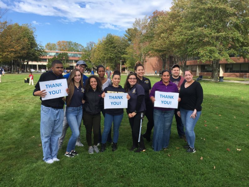 A photo of NECC students outside on the Haverhill campus smiling and waving to the camera