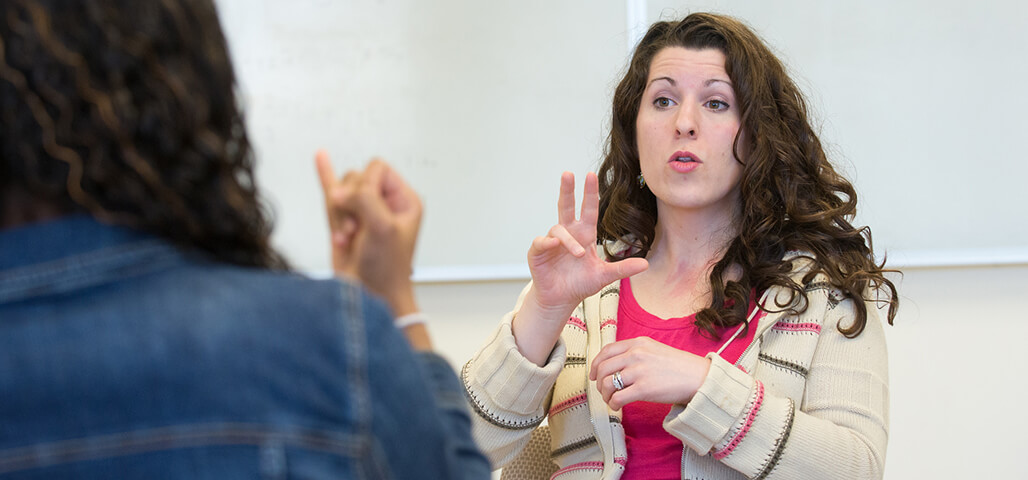 An American Sign Language Studies student practicing signing to another person.