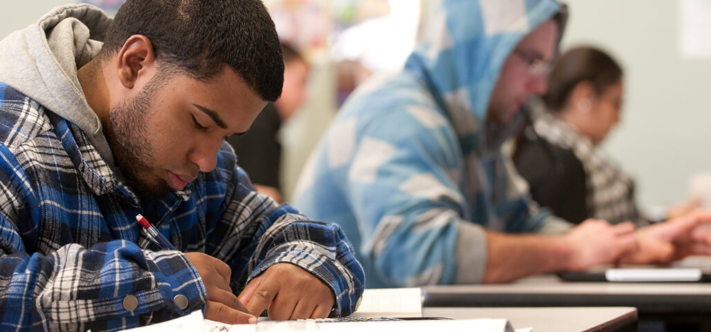 A young man working intently on an exam.