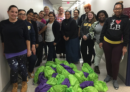 Fourteen students stand around a pile of bags they collected during a service learning project.